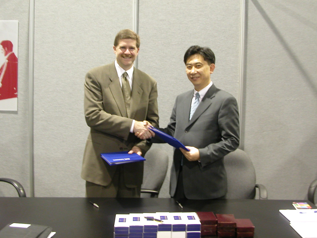 Jin Woo Seo (on right), vice-president of SK Telecom, and John Stratton (on left), vice-president of Verizon Wireless, are shown signing a MOU for cooperation in the EV-DO service area